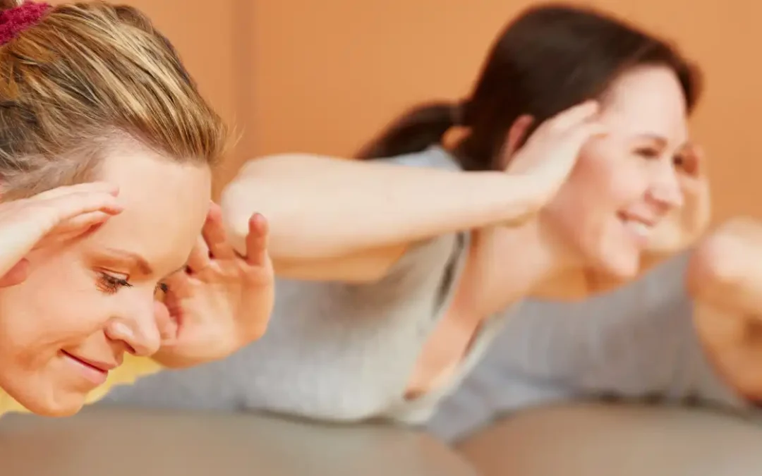 Drei Frauen liegen bäuchlings auf dem Boden und heben ihre Arme und den Oberkörper nach oben.
